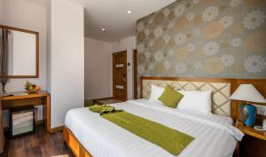 um quarto com uma grande cama branca e um cobertor verde em Richico Apartments And Hotel em Da Nang