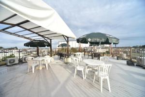a deck with white tables and chairs and umbrellas at Hotel Nomad - Vacation STAY 73941v in Hitachi