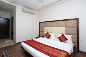 a bedroom with a large bed with red pillows at OYO Asian Hospitality Near Aravali Biodiversity Park in Gurgaon
