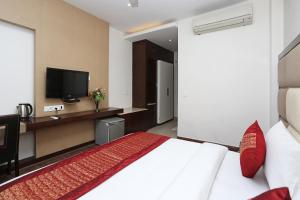 a hotel room with a bed and a flat screen tv at OYO Asian Hospitality Near Aravali Biodiversity Park in Gurgaon