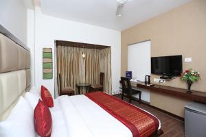 a hotel room with a bed and a desk and a television at OYO Asian Hospitality Near Aravali Biodiversity Park in Gurgaon