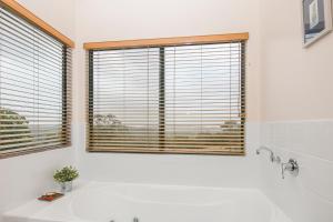 La salle de bains blanche est pourvue d'une baignoire et d'une grande fenêtre. dans l'établissement Karrak Reach Forest Retreat, à Denmark