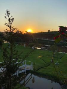 a sunset over a park with a pond and a bridge at Sítio Por do Sol in Piçarras