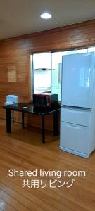 eine Küche mit einem weißen Kühlschrank und einem Tisch in der Unterkunft Inn Komachiya - Vacation STAY 90943v in Senboku