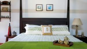 a bedroom with a bed with a green comforter at Clayfingers Art Cottage in Trichūr