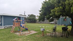 um parque infantil num quintal ao lado de uma árvore em Quiet Condo near Laguna Madre C em Corpus Christi