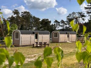 dos casas móviles en un campo con árboles en el fondo en Naturcamping Lüneburger Heide - Chalets & Tiny Häuser en Soltau