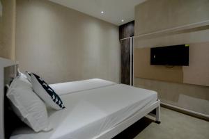 a bedroom with a white bed with a tv on the wall at Abalone 6 BHK Villa by Stayscape in Kīhīm