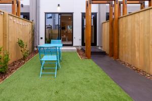 a patio with a blue table and chairs on grass at Beachside Haven 1 bed 1 bath in Christchurch