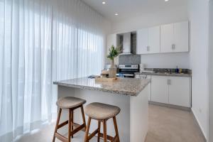 a kitchen with white cabinets and a counter with two stools at New villa by the beach! in Boca del Soco