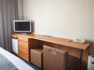 a room with a desk with a television and a phone at Vessel Hotel Kurashiki in Kurashiki