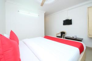 a bedroom with a red and white bed and a tv at Hotel Cozy Residency in Jabalpur