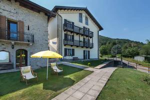 una casa con due sedie e un ombrellone in cortile di B&B Casa Arcangeli a Bracca