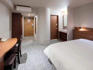 um quarto com uma cama, uma secretária e um lavatório. em Vessel Hotel Miyakonojo em Miyakonojo