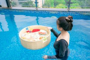 a woman sitting in the water with a basket in a swimming pool at 22Land Residence Hotel & Spa Ha Noi in Hanoi