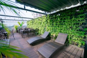 un patio con sillas, mesas y una pared verde en 22Land Residence Hotel & Spa Ha Noi en Hanói