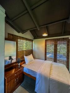 a bedroom with a bed and a mirror and windows at Beragala Serene Villa in Beragala