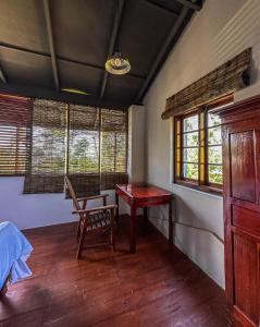 a room with a table and a chair and windows at Beragala Serene Villa in Beragala