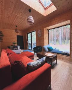 una sala de estar con sofás rojos en una cabaña de madera en Woodland, en Kamieńczyk