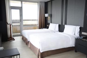 2 Betten in einem Hotelzimmer mit einem großen Fenster in der Unterkunft Crowne Plaza Shanghai Anting, an IHG Hotel - 15 minutes drive to FE in Jiading