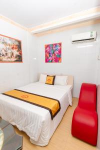um quarto com uma cama e uma cadeira vermelha em Motel Hoài An em Can Tho