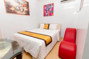 Habitación pequeña con cama y silla roja. en Motel Hoài An en Can Tho
