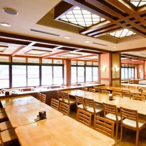 a restaurant with wooden tables and chairs and windows at Asoviva Nagano Park in Nagano