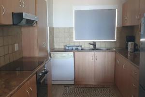 a kitchen with a sink and a white dishwasher at Sunset View 23 in Langstrand