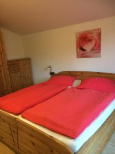 1 dormitorio con 1 cama grande de madera con sábanas rojas. en Landhaus Alpensee 2, en Oberstdorf