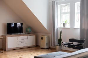 a bedroom with a tv on a dresser and a window at Apartment mit Parkblick & Massagestuhl in Leipzig