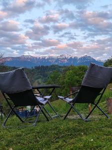 two chairs sitting in the grass with mountains in the background at The Sun Chalet by Touch the Sky in Moieciu de Jos