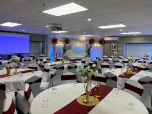 a banquet hall with white tables and chairs and a screen at Airport Gateway Hotel in Auckland