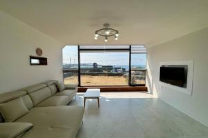 a living room with a couch and a tv and a window at Sunyeonchae in Jeju