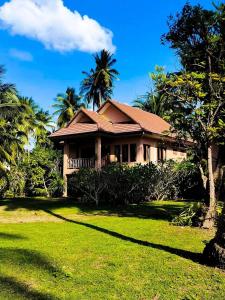 a house with a green lawn and palm trees at Links Sunset Beach House in Amphoe Koh Samui