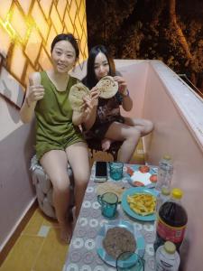 charming nubian guest house في أسوان: كانتا جالستين على شرفة مع أطباق من الطعام