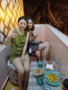 zwei Frauen sitzen auf einem Balkon mit einem Teller Essen in der Unterkunft charming nubian guest house in Assuan