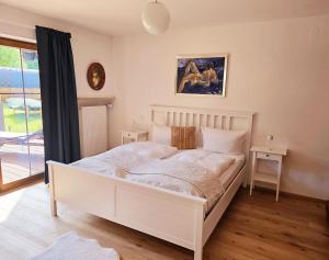 a white bed in a room with a window at Chalet Anna in Unterwössen