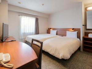 a hotel room with two beds and a desk at Vessel Hotel Miyakonojo in Miyakonojō