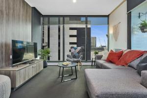 a living room with a couch and a flat screen tv at Spencer St Serenity Chic Urban Escape in the CBD in Melbourne