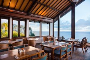 Blue Point Resort and Spa في أُلُواتو: مطعم به طاولات وكراسي ومطل على المحيط
