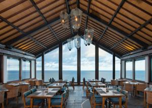 Blue Point Resort and Spa في أُلُواتو: مطعم به طاولات وكراسي ومطل على المحيط