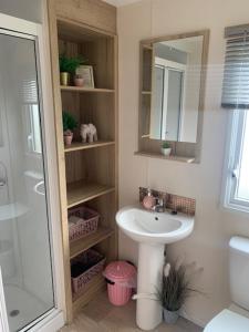 La salle de bains est pourvue d'un lavabo, d'un miroir et d'une douche. dans l'établissement The Wardens Retreat - Tattershall Lakes Country Park, à Tattershall