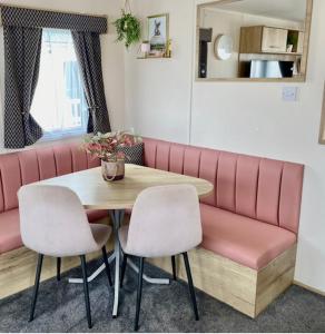 een tafel met 2 stoelen en een roze bank bij The Wardens Retreat - Tattershall Lakes Country Park in Tattershall