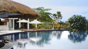 - une piscine dans un complexe avec des parasols dans l'établissement Blue Point Resort and Spa, à Uluwatu