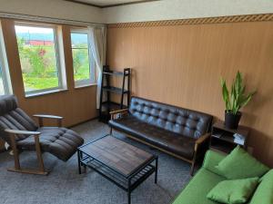 a living room with a leather couch and a coffee table at Other Side House in Nakafurano