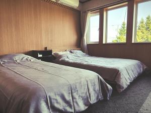 two beds in a room with two windows at Other Side House in Nakafurano