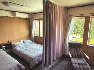 ein Schlafzimmer mit einem Bett, einem Stuhl und einem Fenster in der Unterkunft Other Side House in Nakafurano