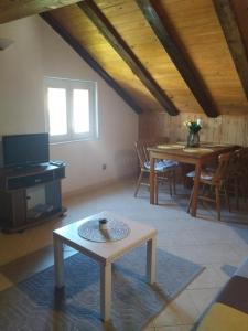 ein Wohnzimmer mit einem Tisch und einer Holzdecke in der Unterkunft Family apartments TOMY in Punat