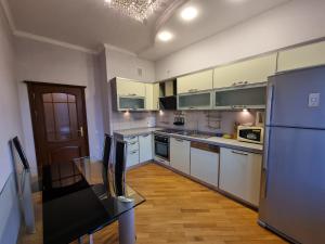 cocina con armarios blancos y nevera de acero inoxidable en Winter Park apartment, en Baku
