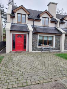 una casa con una puerta roja y un banco en 5 Sruthan Beag Dingle, en Dingle